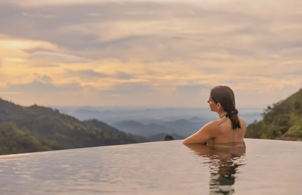 Guest relaxing in the infinity pool at 98 Acres Resort & Spa overlooking Ella’s mountain landscape.