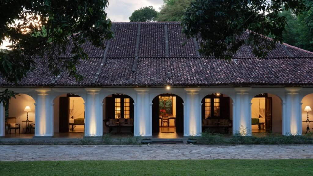 Illuminated colonial-style exterior of Adigar’s Manor in Kandy, surrounded by lush gardens.