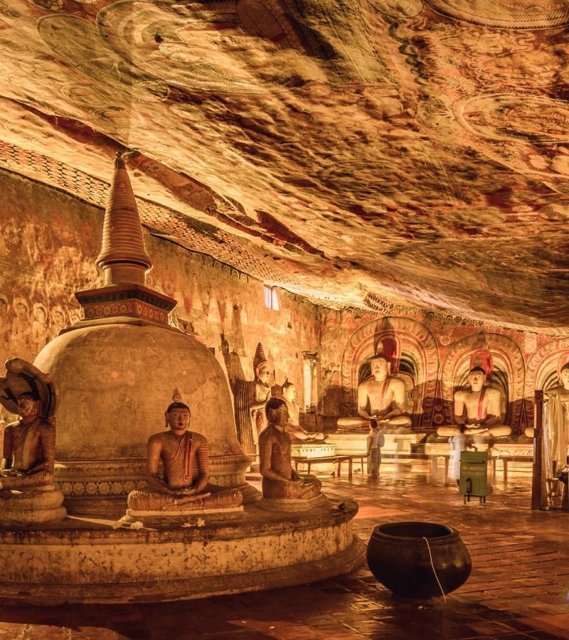Ancient Buddha statues, stupa and ceiling paintings inside Dambulla Cave Temple.