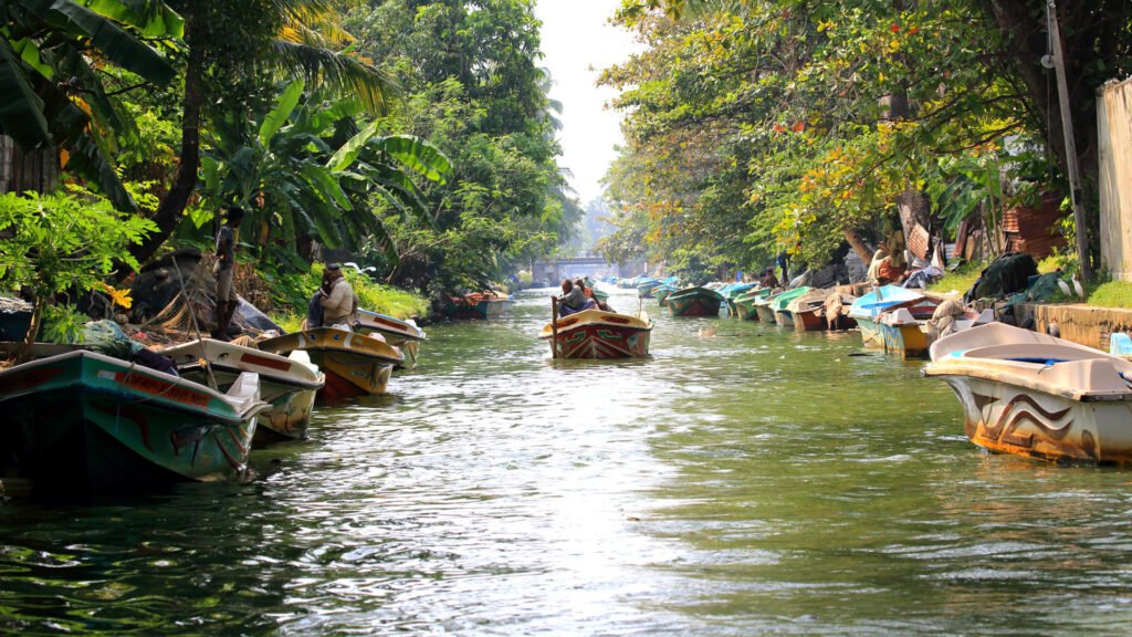 Boats travelling along the historic Dutch Canal surrounded by tropical greenery in Negombo.