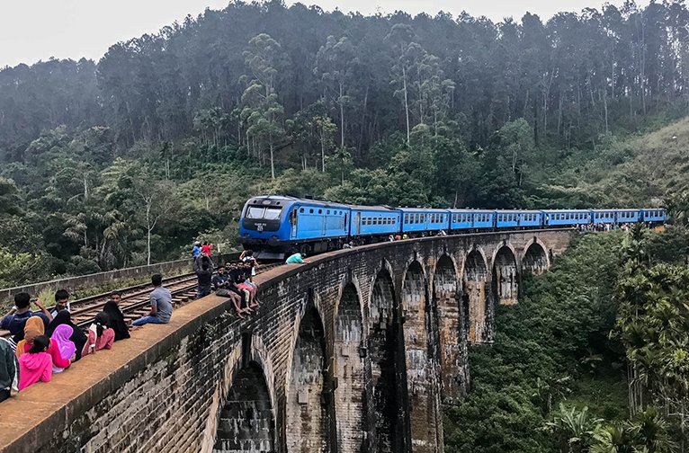 Blue train crossing the Nine Arch Bridge in Ella, Sri Lanka.