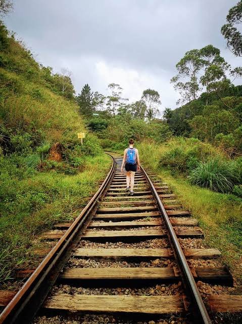 Traveller walking along railway tracks surrounded by greenery in Ella, Sri Lanka.