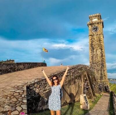 Tourist posing beside the historic Galle Fort Clock Tower in Sri Lanka.