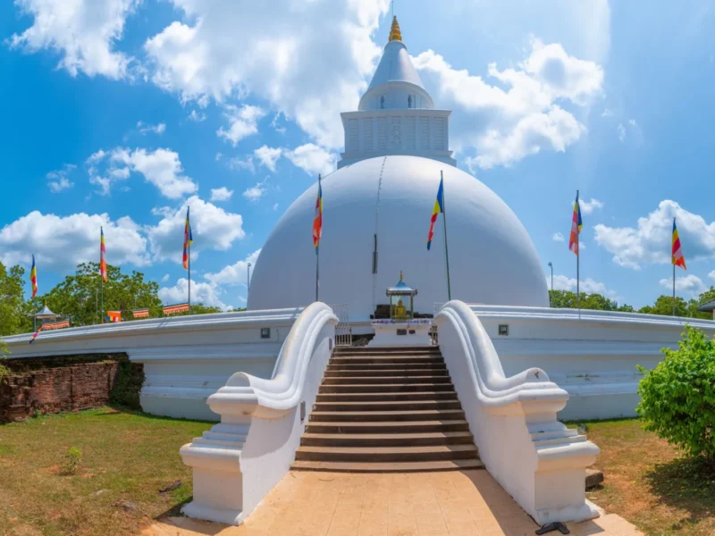 White Buddhist stupa surrounded by flags and gardens in Kataragama, Sri Lanka.