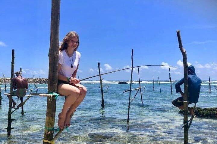 Tourist experiencing traditional stilt fishing on Sri Lanka’s southern coast.