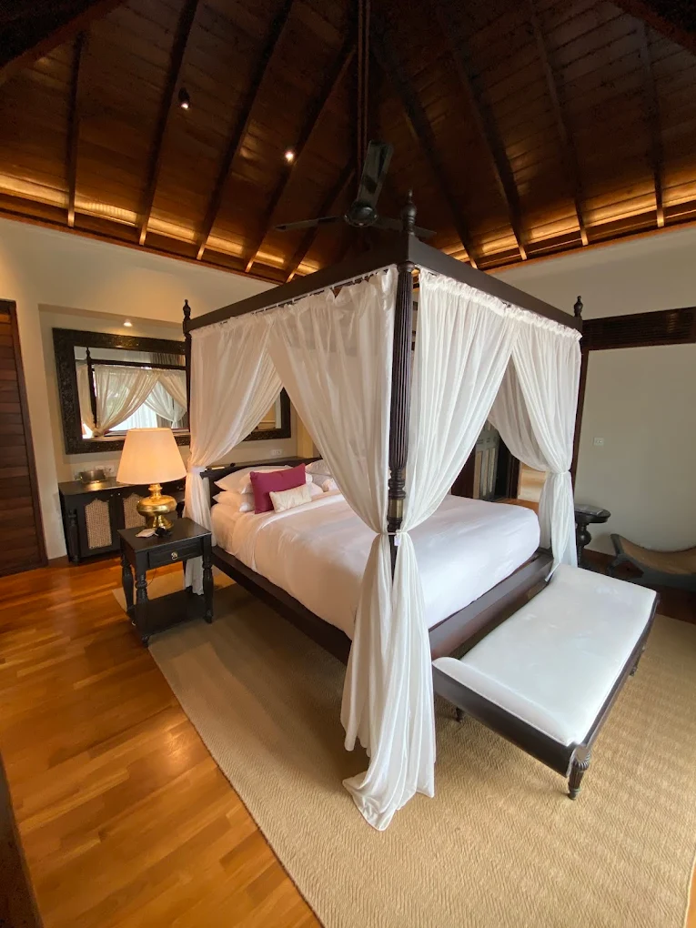 Elegant four-poster bedroom with warm wooden interiors at Uga Ulagalla.