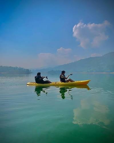 Travellers kayaking across a calm Castlereagh lake in Sri Lanka.